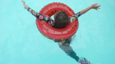 Summer child boy relax at aquapark. Happy Asian kid boy in rubber ring bathes swimming on pool blue water having fun in resort, Summertime vacation concept, top view