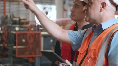 Çelik çelik fabrikası endüstrisinde iki mühendis birlikte konuşuyor. Metal levha damgalama makinesini ve takım çalışması konseptini korumak için ayakta duran mühendis.