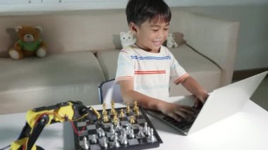 Satranç oynamak için dizüstü bilgisayardaki robot makine koluna Asya 'lı küçük çocuk programlama kodu, BTMM eğitimi E-öğrenme, Ders kontrolü robot kolu edinen komik çocuklar, Teknoloji Bilimi eğitimi alan çocuklar.
