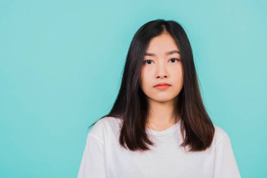 Asyalı güzel bir genç kadının yakın yüzü, mutlu Taylandlı bir kadının portresi kameraya gülümseyen, stüdyo görüntüsü mavi arka planda izole edilmiş.