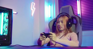 You win. Gamer using joystick controller plays online video game with computer neon lights she winning, woman wear gaming headphones playing live stream esports games console at home celebrating win