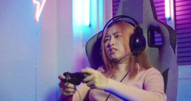 Kaybediyorum. Oyun oynayan oyuncu bilgisayar ışıklarında joystick ile çevrimiçi oyun oynuyor. Başarısız oyun bitti, mutsuz Asyalı kadın oyun kumandanını oynuyor ve evinde hayal kırıklığına uğradı.