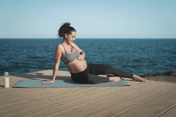 次の海で彼女の妊娠中の腹を愛撫幸せな若い女性 健康ライフスタイルと妊産婦の概念 — ストック写真