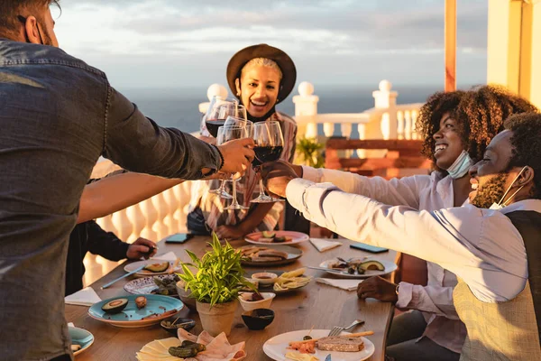 Teman Teman Muda Bersulang Dengan Gelas Anggur Merah Pada Hidangan — Stok Foto