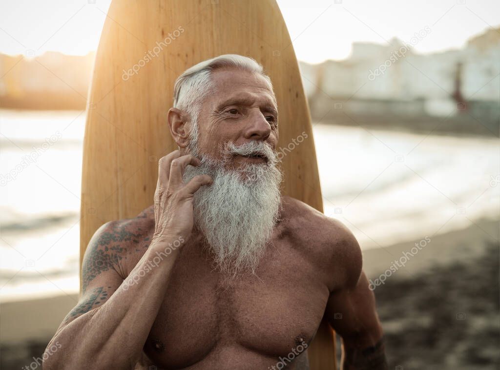Fit senior man having fun practicing surf on tropical beach - Elderly healthy people lifestyle and extreme sport concept