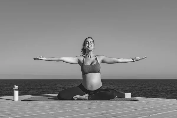 海の横でヨガセッションを行う若い妊婦 瞑想と妊産婦の概念 黒と白の編集 — ストック写真
