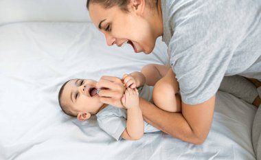 Mutlu anne küçük bebeğiyle yatakta eğleniyor - aile ve annelik kavramı
