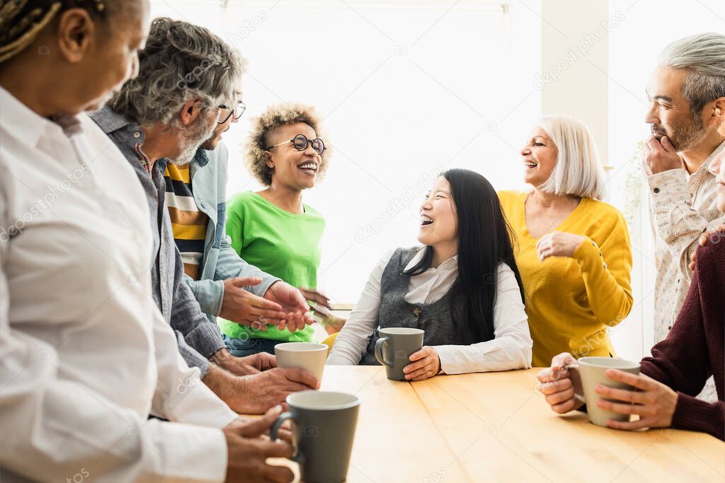 Happy multiracial people with different ages and ethnicities having fun drinking a cup of coffee at home