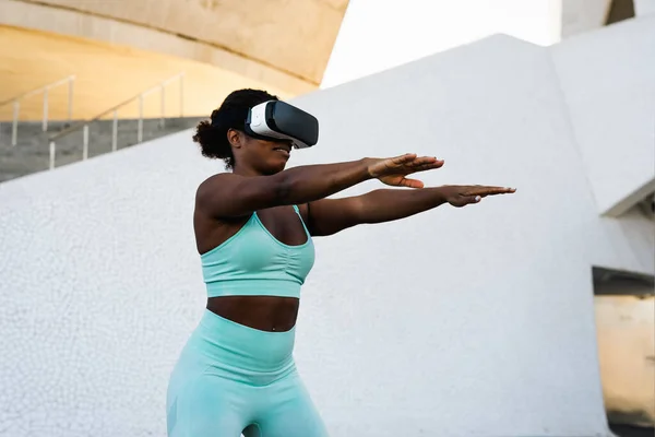 Happy fit African woman using futuristic virtual reality glasses during training session - Technology and Innovated workout concept