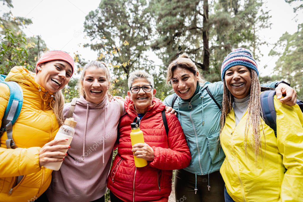 Group of women with different ages and ethnicities having fun walking in the woods - Adventure and travel people concept