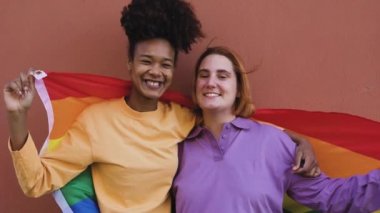 Happy gay couple celebrating pride holding rainbow flag outdoor - Lgbt and love concept