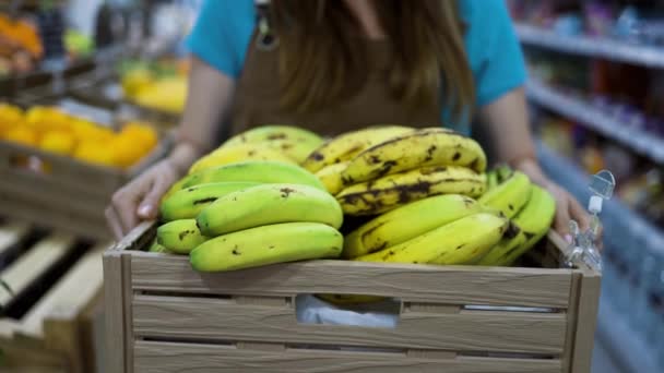 新鮮なバナナを入れた箱を持ったスーパーで働く女性 — ストック動画