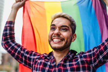 LGBTQ topluluğunun gökkuşağı bayrağı taşıyan gurur festivalini kutlayan mutlu gay adam.