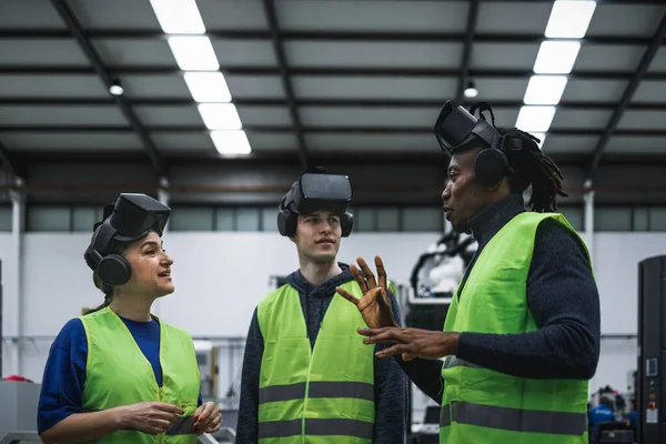 Team of engineers having simulation experience with futuristic virtual reality glasses inside robotic factory - Tech industry and metaverse concept