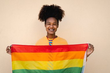 Mutlu Afrikalı eşcinsel kadın dışarıda gökkuşağı bayrağı taşıyarak gururu kutluyor - LGBT kavramı