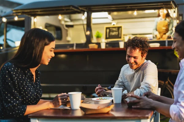 Happy multiracial people having fun eating in a street food truck market