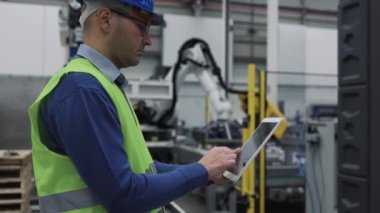Robot fabrikasında çalışan mühendis, projeyi akıllı tablet - teknoloji endüstrisi konsepti üzerine izlerken