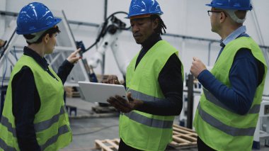 Robot fabrikasında çalışan mühendisler tablet-teknoloji endüstrisi konseptinde projeyi izliyorlar.