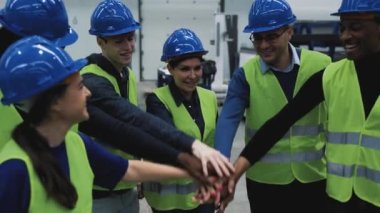 Çok ırklı mühendislerden oluşan bir ekip robot fabrikasında el ele tutuşuyor.