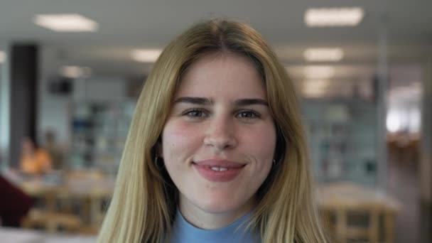 Feliz Jovencita Sonriendo Cámara Mientras Está Pie Dentro Biblioteca Universitaria — Vídeo de stock