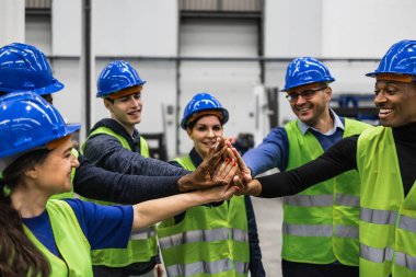 Çok ırklı mühendislerden oluşan bir ekip robot fabrikasında el ele tutuşuyor.