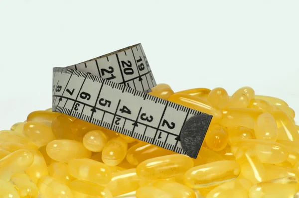 Coconut oil capsule and metric tape — Stock Photo, Image