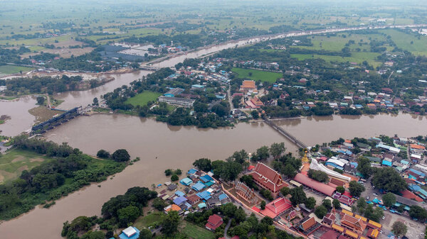 Flood waters overtake a house and rice field at Central of Thailand in 2021. Many buildings are submerged in water. Photo disaster from above view by drone