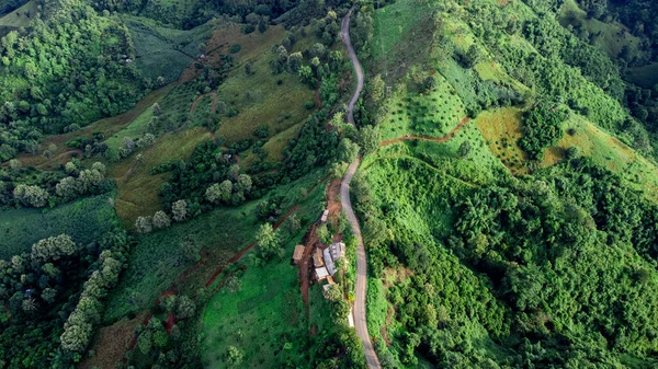 Aerial view of sky road over top of mountain with fog and green jungle after raining in morning, doi sakad, Pua, Nan, Thailand. The transportation by road across beautiful mountain. Shot from drone.