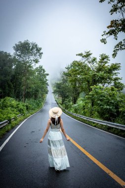 Nan, Thiland- Ekim 2021 - 1715 gökyüzü yolunun arka planındaki sisli dünyaya yağmurlu mevsimde sis dolu güzel bir kadın yürür..