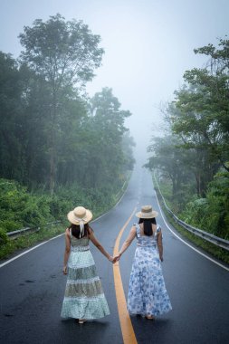 Nan, Thiland- Ekim 2021 - 1715 gökyüzü yolunun arka planındaki sisli dünyaya yağmurlu mevsimde sis dolu güzel bir kadın yürür..