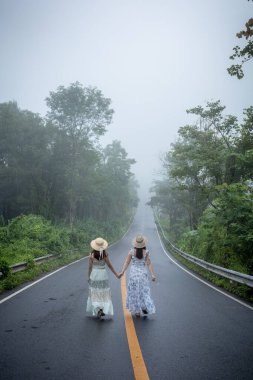 Nan, Thiland- Ekim 2021 - 1715 gökyüzü yolunun arka planındaki sisli dünyaya yağmurlu mevsimde sis dolu güzel bir kadın yürür..
