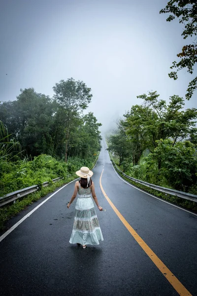 Nan, Thiland- Ekim 2021 - 1715 gökyüzü yolunun arka planındaki sisli dünyaya yağmurlu mevsimde sis dolu güzel bir kadın yürür..