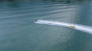 Sichon plajı, Tayland - Kasım 2021: Havadan kuş bakışı: Açık deniz turkuazında yüksek hızda seyreden tanımlanamayan muz teknesinin tanımlanamayan jet ski görüntüsü.