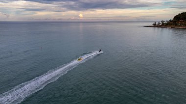 Gökyüzü kuşunun gözleri muz teknesini kaplayan jet ski görüntüsü turkuazlı berrak su denizinde yüksek hızda seyrediyor..