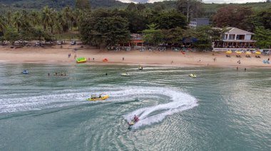 Gökyüzü kuşunun gözleri muz teknesini kaplayan jet ski görüntüsü turkuazlı berrak su denizinde yüksek hızda seyrediyor..