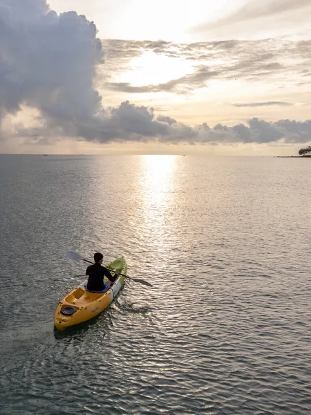 空中から見たシーカヤックの男 黄色と青のコーカサススポーツマン海岸沿いの景色の海で漕ぐカヤック — ストック写真