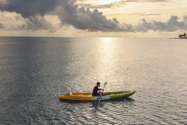Man on sea Kayaker from Aerial View. Caucasian Sportsman in the Yellow and Blue Kayak Paddling on the Scenic sea Along the Shore.