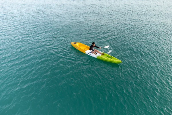 空中から見たシーカヤックの男 黄色と青のコーカサススポーツマン海岸沿いの景色の海で漕ぐカヤック — ストック写真