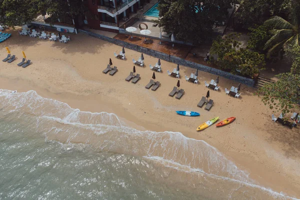 Kumlu sahil ve okyanusta dalgalı berrak turkuaz deniz manzarası.