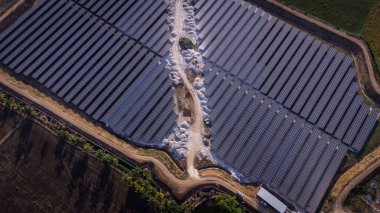 Gece boyunca temiz enerji üreten bir güneş çiftliğinin hava görüntüsü. Tüm bölgede görülebilir