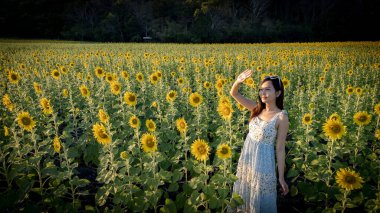 Ayçiçekli mutlu kız doğanın tadını çıkarıyor ve yaz ayçiçeği tarlasında gülümsüyor. Özgürlük kavramı ve...
