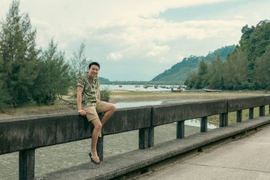 Şapkalı genç adam, Laem 'deki bir dağ nehrinin üzerinden geçti. Ulusal Park, Ranong, Tayland.