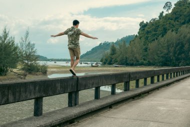 Şapkalı genç adam, Laem 'deki bir dağ nehrinin üzerinden geçti. Ulusal Park, Ranong, Tayland.