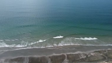 Yumuşak dalgalar ve kumlu kumsalda mavi okyanus hareketi. Ranong, Tayland 'daki Laem Son Ulusal Parkı' nda kara kum plajı.