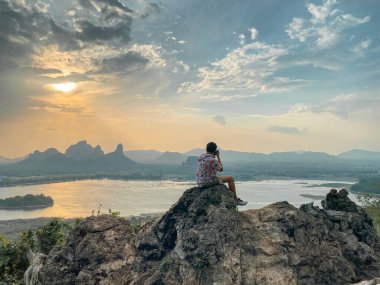 Dağ manzaralı maceraperest adam. Phu Sub Lek, Lopburi, Tayland 'ın gizli mücevheridir. Khao Jeen Lae' nin görülemeyen günbatımı gökyüzünü göl suyunun üzerinde görmek için..