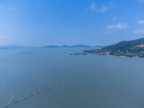 Fishing boats in a fishing village reflecting on the water. Life of a fishing village in shore of Songkhla, Thailand from drone bird eye view.