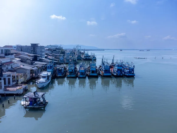 Fishing boats in a fishing village reflecting on the water. Life of a fishing village in shore of Songkhla, Thailand from drone bird eye view.
