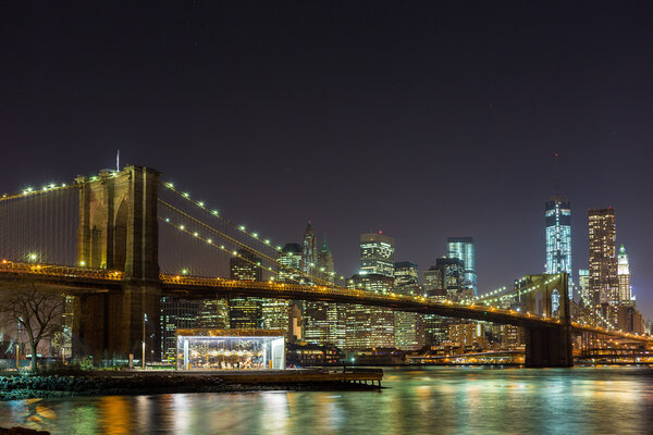 Brooklyn Bridge at night with Lower Manhattan in background.