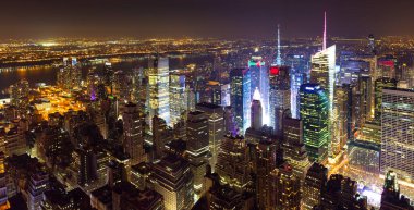 Midtown West Manhattan 'ın üzerinden gece Hudson Nehri' ne doğru New York City 'ye doğru yükseliyor. Birçok bina, yüksek binalar ve gökdelenler içeren New York eyaletinin başkenti..