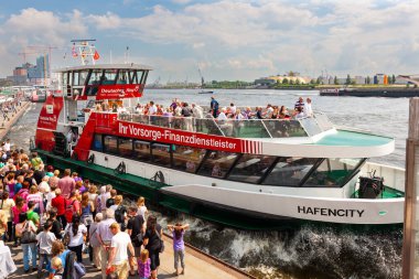 Hamburg, Almanya - 12 Temmuz 2011: Hamburg Limanı. Büyük bir kalabalık bir sonraki vapurun gelmesini beklerken, bir tur teknesi demir alıyor..